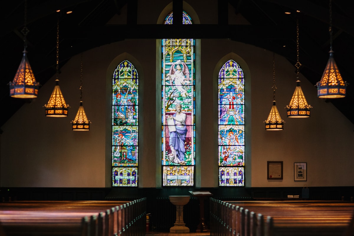 Stained glass window inside a traditional English church, sunlight streaming through coloured panels